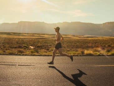 man in black shorts running on gray asphalt road during daytime